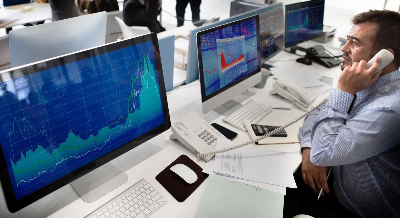 A man sitting at a desk with several computers.